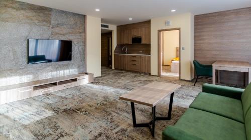 a living room with a couch and a tv at Spa & Wellness Hotel Fitak**** in Liptovský Ján