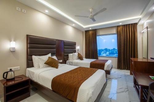 a hotel room with two beds and a window at PARKKAVAN TOWERS in Tiruchchirāppalli