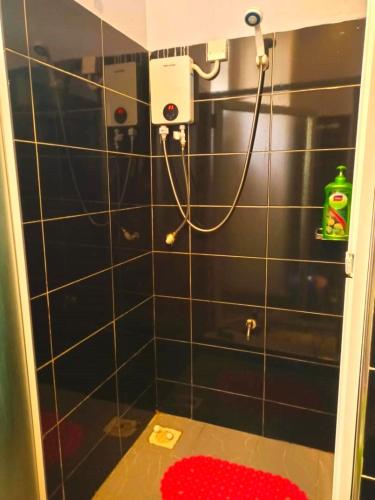 La salle de bains est pourvue de carrelage noir, d'une douche et d'un tapis rouge. dans l'établissement Serene Homes 05, à Kampala