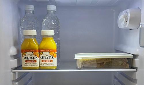 3 bottiglie di succo d'arancia e pane in un frigorifero di Hanok Dasi Bom a Gyeongju