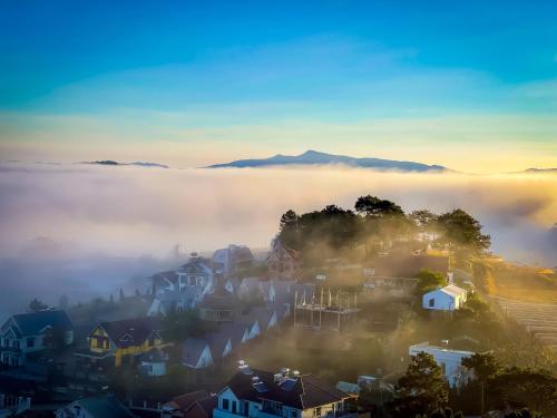 a city in the fog with mountains in the background at Dallas Hotel Dalat in Da Lat