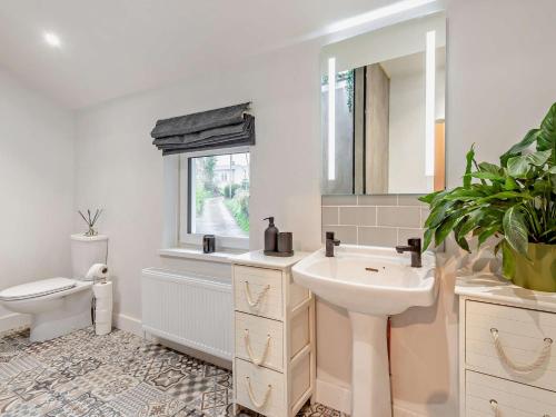 Un baño con lavabo, inodoro y espejo. en 2 Bed in Maryport 91132, en Dearham
