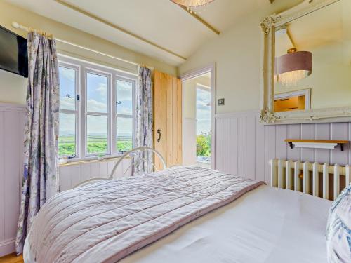 a bedroom with a bed with a mirror and a window at 1 Bed in Boscastle 90818 in Camelford