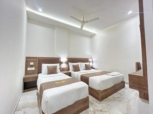 Duas camas num quarto com paredes brancas em MIG SUITES em Mumbai