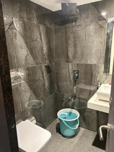 a bathroom with a shower with a bucket next to a toilet at MIG SUITES in Mumbai