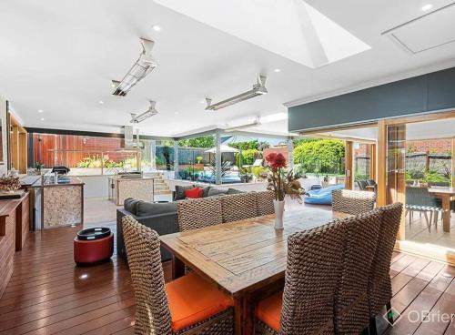 a kitchen and living room with a wooden table and chairs at Luxury Family Holiday Rental On the Mornington Peninsula in Frankston South