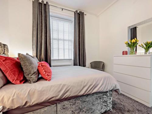 a bedroom with a bed with red pillows and a window at 1 Bed in Allonby 91113 in Allonby