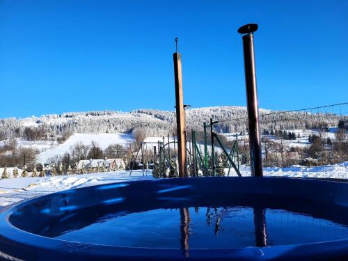 a hot tub in the snow with a mountain in the background at Domki na Sudeckiej Polanie in Stronie Śląskie