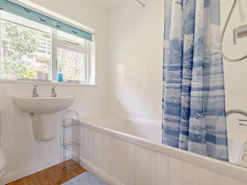 ein Bad mit einem Waschbecken, einer Badewanne und einem Fenster in der Unterkunft 3 Bed in Newton Ferrers 90945 in Newton Ferrers