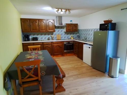 une cuisine avec une table et un réfrigérateur dans l'établissement Grande maison 7 chambres, à Cheylade