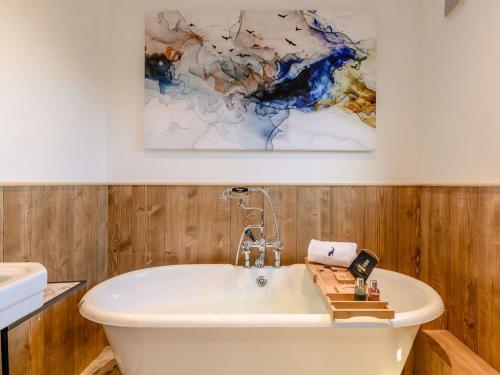 Finghall的住宿－2 Bed in Leyburn 91102，浴室设有白色浴缸和墙上的绘画作品