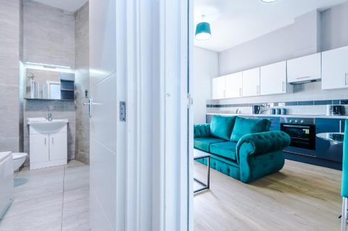 ein Wohnzimmer mit einem grünen Sofa und einer Küche in der Unterkunft Stylish Apartment located in the City Centre of Liverpool - Sleeps 5 in Liverpool