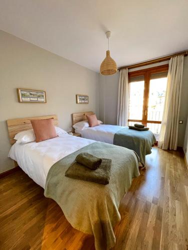 two beds in a bedroom with wooden floors at Apartamento en el centro de Benasque con piscina in Benasque