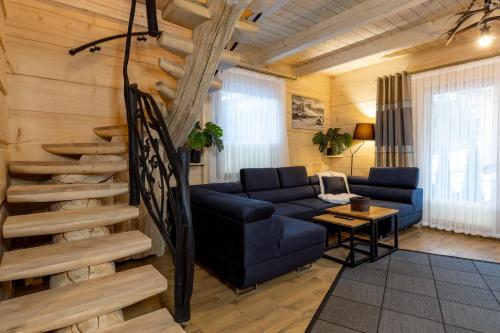a living room with a blue couch and a staircase at Leśny Dwór Premium Chalets Zakopane in Murzasichle