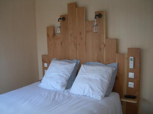 1 cama con 2 almohadas blancas y cabecero de madera en Chambre nature en Arès