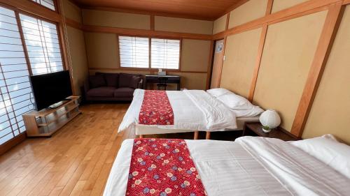 um quarto com duas camas e um sofá e uma televisão em Hondori Inn em Hiroshima