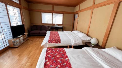 a room with two beds and a couch and a tv at Hondori Inn in Hiroshima