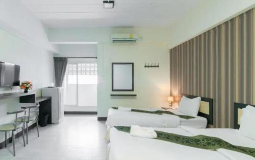 ラートクラバンにあるB9 Airport Residentのベッド3台とテーブルが備わるホテルルームです。