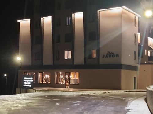 um edifício à noite com neve em frente em Apart Hotel Zlatni Javor, Apartment 410 em Jahorina