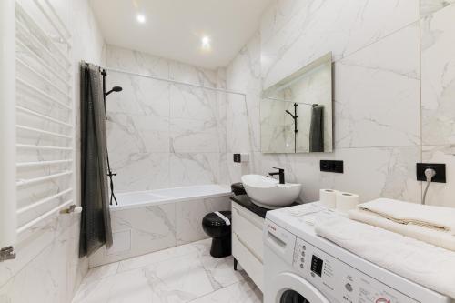 a white bathroom with a sink and a tub and a toilet at Luxury Apartments-Belochka in Uzhhorod