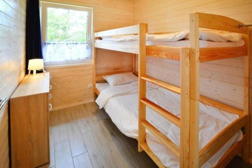 two bunk beds in a wooden room with a window at Comfortable holiday home for 4 people Ustronie Morskie in Ustronie Morskie