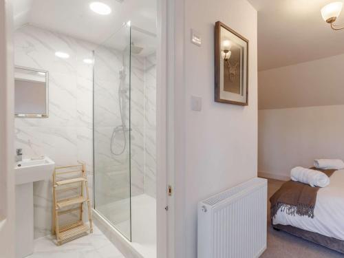 a bathroom with a shower and a bed and a sink at 4 Bed in Wick 91390 in Wick