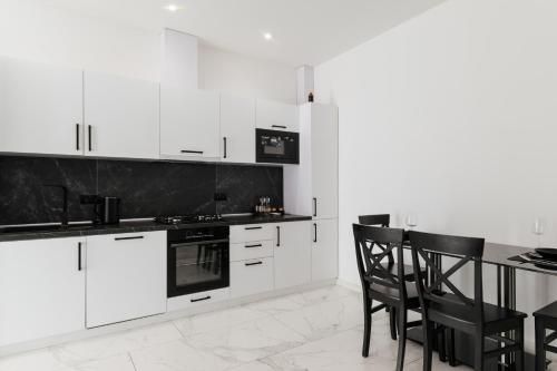 a kitchen with white cabinets and a table with chairs at Luxury Apartments-Belochka in Uzhhorod
