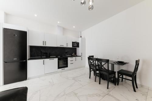 a kitchen with white cabinets and a table and chairs at Luxury Apartments-Belochka in Uzhhorod