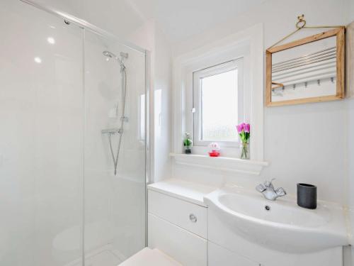 a white bathroom with a sink and a shower at 1 Bed in Dalry 91418 in Dalry