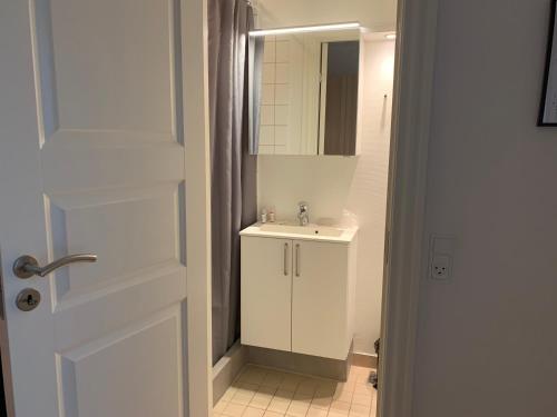a white bathroom with a sink and a mirror at Thyborøn Hotel in Thyborøn