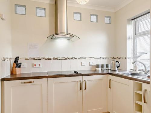 una cocina con armarios blancos y fregadero en 3 Bed in Stalham 91479, en Stalham