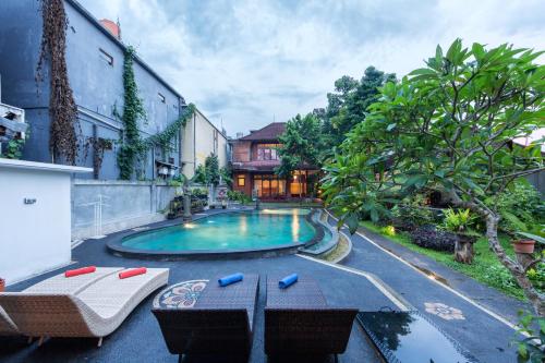 a swimming pool with two chairs and a table at Rahayu Hanoman Ubud in Ubud