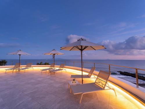 a group of lounge chairs and umbrellas on a balcony at Atagawa Ocean Resort in Higashiizu