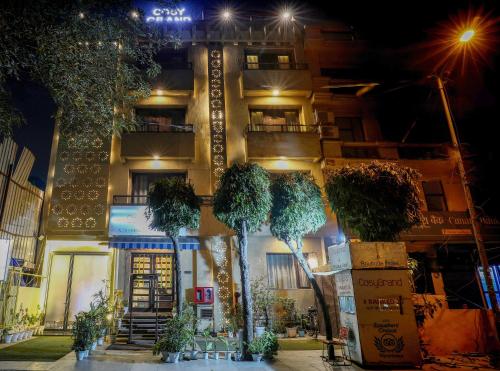 a building with trees in front of it at night at Cosy Grand, Near Chanakyapuri, Embassy Area in New Delhi