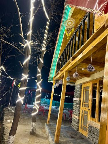 a tree decorated with lights in front of a building at Sainj Riverside Cottages in Sainj