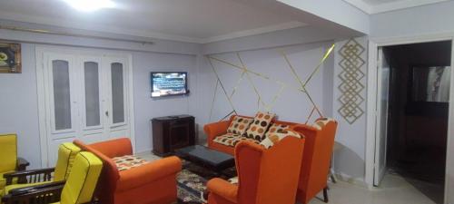 a living room with two orange chairs and a tv at شاليه في قرية هيلو بيتش في الكيلو ٥٠ in Borg El Arab