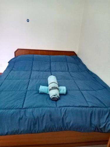 a bed with a blue comforter and a towel on it at Nontharat Mansion in Nonthaburi