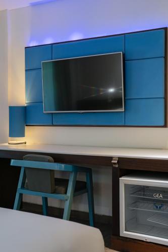 a tv on a wall with a chair and a stool at Kuta Beach Club Hotel in Kuta