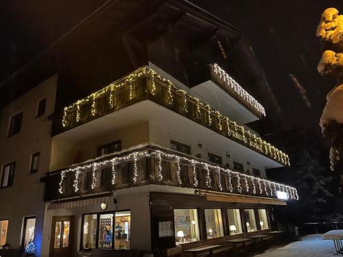 un edificio decorado con luces de Navidad por la noche en Pension Alpina, en Obsteig