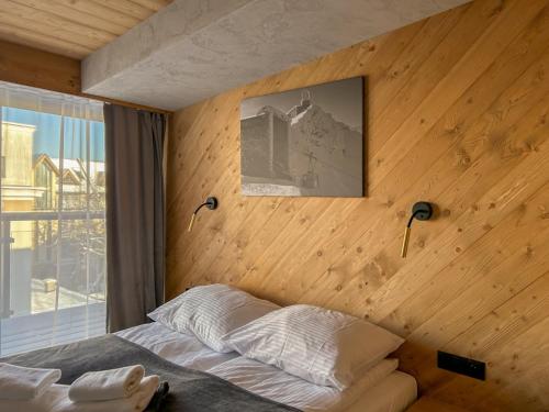 a bedroom with a wooden wall with a bed and lamps at Apartamenty Krupówki 20 in Zakopane
