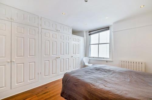 Chancery's Loft Private Apartment في لندن: غرفة نوم بجدران بيضاء وسرير ونافذة