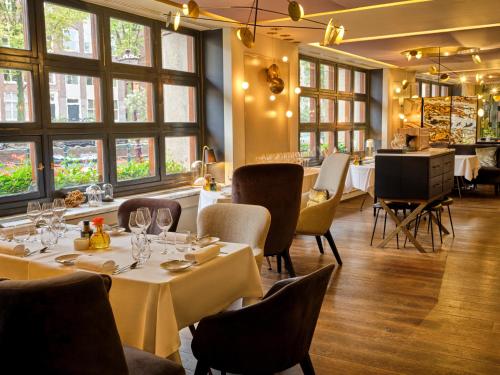 a restaurant with tables and chairs and windows at Sofitel Legend The Grand Amsterdam in Amsterdam