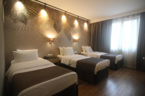 イスタンブールにあるリヴァ ホテル タクシムのベッド2台、壁に照明が備わるホテルルームです。