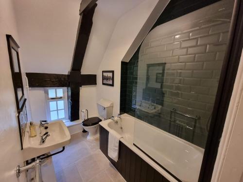 La salle de bains est pourvue d'une baignoire, d'un lavabo et de toilettes. dans l'établissement Gardener's Cottage, Knebworth Park, à Knebworth