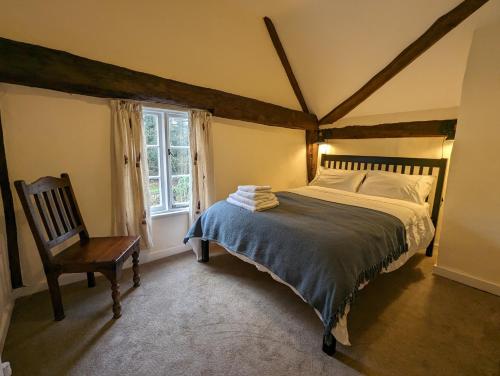 a bedroom with a bed and a chair and a window at Gardener's Cottage, Knebworth Park in Knebworth