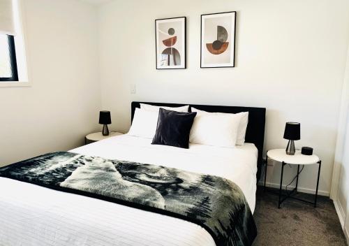 a bedroom with a black and white bed and two tables at Close to Arena and not far away from Railway station onsite park rare to find in Christchurch