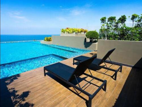 two chairs sitting on a deck next to a swimming pool at The Blu X Seaview บางแสน F5 R140 in Ban Bang Saen (1)