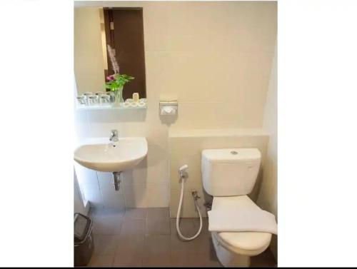 uma casa de banho com um WC branco e um lavatório. em Mugiwara Hotel&Apartment em Batulicin