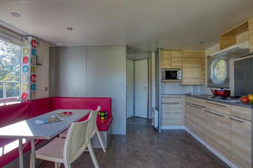 - une cuisine avec un banc rouge et une table dans une pièce dans l'établissement Camping Brin d'Amour, à Les Eyzies-de-Tayac