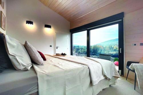 a bedroom with a large bed with a large window at RA House Plitvice Lakes in Bročanac